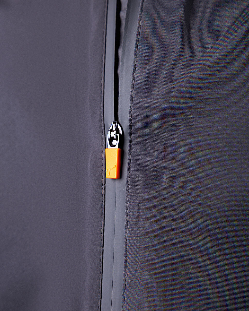 Close-up of a zipper on a dark gray jacket with an orange zipper pull.